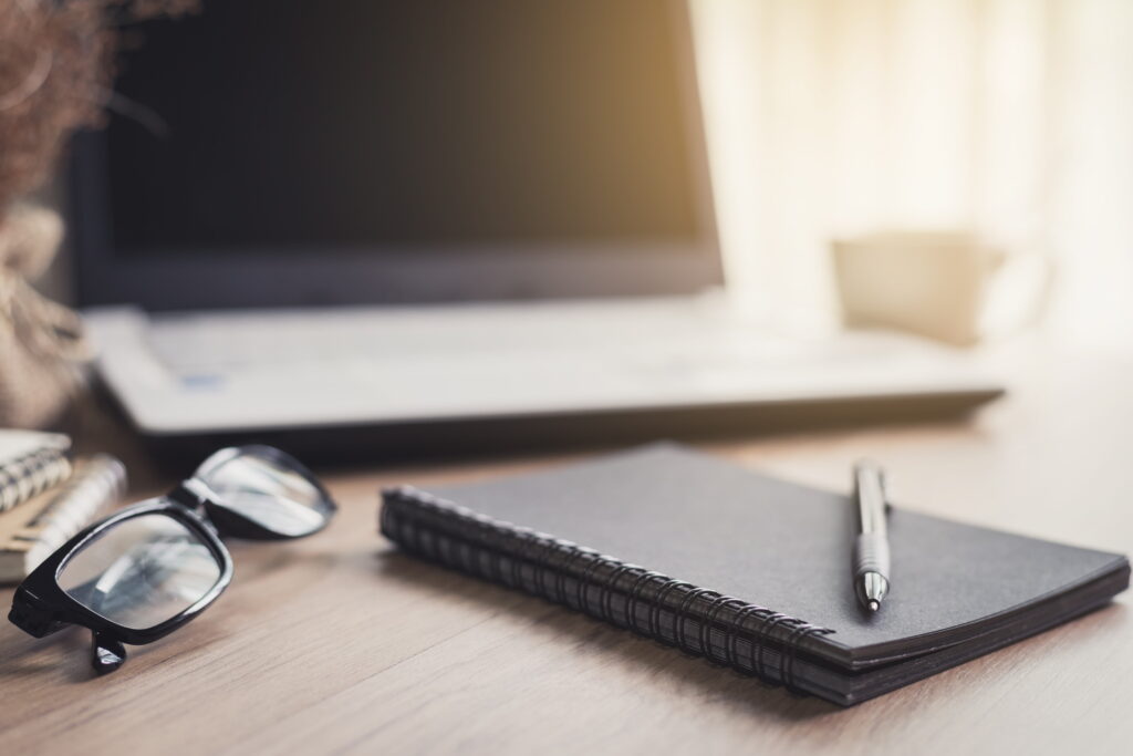 Bloco de notas e computador sobre uma escrivaninha